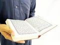 Photo of man holding a Koran ready for Ramadan. Arabic on the cover is translated as the Qur`an