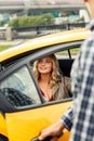 Photo of man opening taxi door where blonde sits on summer Royalty Free Stock Photo
