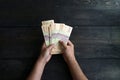 Photo of a man`s hand counting Indonesian five thousand rupiah in a bunch