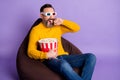 Photo of man sit beanbag bucket popcorn bite finger wear 3d glasses yellow sweater isolated violet background