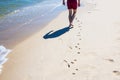 Photo of man walking on the hot sandy beach leaving footsteps next to the dog`s footprints Royalty Free Stock Photo