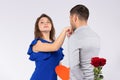 Photo of man who kisses the hand of his beloved woman and holds a heart and red roses behind his back. Gray background. Royalty Free Stock Photo