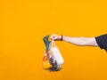 Photo of a mans hand holding a pouch with groceries near a yellow wall Royalty Free Stock Photo