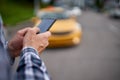 Photo of mans hands with phone in his hands on blurry background taxi