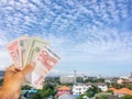 Many currency bangknote in hand with blue sky background