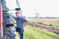 Mature attractive farmer hopping in to drive tractor in field