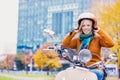 Portrait of mature beautiful woman putting her helmet on to ride motorbike in park
