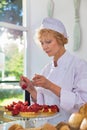 Mature chef arranging fresh strawberry tarts in restaurant