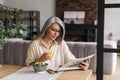 Concentrated woman reading newspaper while drinking juice