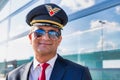 Portrait of mature confident pilot captain wearing eyeglasses in airport