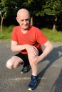 Photo of mature, elderly man sitting in the park and touching his knee by the pain during the day. Royalty Free Stock Photo