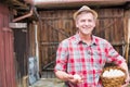 Mature farmer wearing hat while carrying fresh eggs in basket at barn Royalty Free Stock Photo