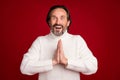 Photo of mature happy excited crazy positive smiling man hold hands in prayer anticipation isolated on red color