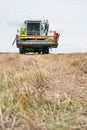 Mature male farmer standing on harvester in field Royalty Free Stock Photo