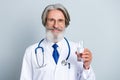 Photo of mature man physician hold glass of water recommend ad wear coat isolated over grey color background Royalty Free Stock Photo