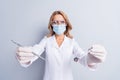 Photo of mature stomatologist woman in face mask doing dental procedure in camera isolated on grey color background