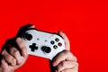 A photo of men hands holding a white gamepad on a bright red background with a place for the advertised text