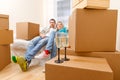 Photo of man and woman sitting on sofa among cardboard boxes with two wine glasses