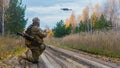 Photo of a mercenary soldier launch a reconnaissance drone on the road in a forest.