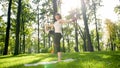 Photo of middle aged smiling woman practising yoga asana. Persong meditating in nature. Balance and harmony of body and