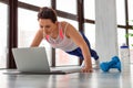 Photo of a middle-aged woman doing push-ups at home in front of a laptop monitor Royalty Free Stock Photo