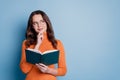 Photo of minded clever creative woman read book finger chin look empty space posing on blue background