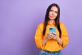 Photo of minded ponder girl with straight hairdo dressed yellow shirt hold smartphone look empty space isolated on Royalty Free Stock Photo