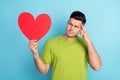 Photo of minded serious young man look heart shape red paper minded isolated on pastel blue color background