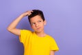 Photo of minded uncertain unsure boy arm touch hair look empty space hmm creative idea solution isolated on purple color Royalty Free Stock Photo