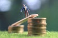 Miniature figure young bussinesman keep trying to get higher income walking at stack of coin at fresh green grass in the morning Royalty Free Stock Photo