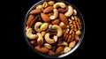 Photo of mixed nuts in a shiny metal bowl on a dark background