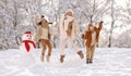 Happy family mother with two little kids holding each other's hands and jumping in snowy park Royalty Free Stock Photo