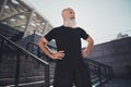 Photo of motivated dedicated bearded old coach man hands hips look away wear t-shirt urban town outdoors