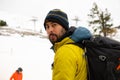 photo of mountaineer with hat, backpack and coat going up ski slope. ski lift in the background Royalty Free Stock Photo