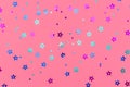 Photo of multi-colored stars glitter sprinkles on pink background. Festive holiday background for your projects. Celebration Royalty Free Stock Photo