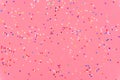 Photo of multi-colored stars glitter sprinkles on pink trendy background. Festive holiday background for your projects. Royalty Free Stock Photo