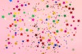 Photo of multi-colored stars glitter sprinkles on pink trendy background. Festive holiday background for your projects. Royalty Free Stock Photo