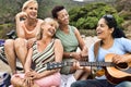 Portrait of multi ethnic old friends singing while playing guitar on the beach Royalty Free Stock Photo