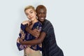 Photo of joyful ladies embrace and enjoy togetherness, being of different of races, looking at camera against background