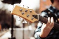 Photo of musician playng on six string fretless bass guitar on the street in front of people.