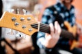 Photo of musician playng on six string fretless bass guitar on the street in front of people.