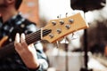 Photo of musician playng on six string fretless bass guitar on the street in front of people.