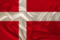 Photo of the national flag of Denmark on a luxurious texture of satin, silk with waves, folds and highlights, close-up, copy space