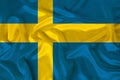 Photo of the national flag of the state of Sweden on a luxurious texture of satin, silk with waves, folds and highlights, close-up Royalty Free Stock Photo