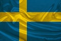 Photo of the national flag of the state of Sweden on a luxurious texture of satin, silk with waves, folds and highlights, close-up Royalty Free Stock Photo