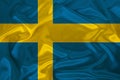 Photo of the national flag of the state of Sweden on a luxurious texture of satin, silk with waves, folds and highlights, close-up Royalty Free Stock Photo