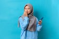 Photo of nervous scared Indonesian woman holding a smartphone with worried expression at camera, sees phobia, afraids of speaking