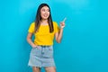 Photo of nice asian girl direct finger empty space advertise clothes collection wear t-shirt denim skirt isolated blue Royalty Free Stock Photo