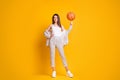 Photo of nice attractive sportive brown hair woman spinning ball playing basketball isolated over bright yellow color Royalty Free Stock Photo