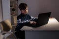 Photo of nice boy in sweater sitting infront of the computer doing homework. Royalty Free Stock Photo